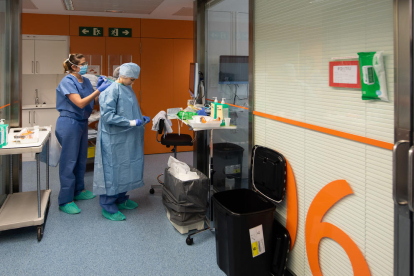 Una profesional sanitaria se protege antes de entrar en una habitación de un positivo por coronavirus en el Hospital Clínic.