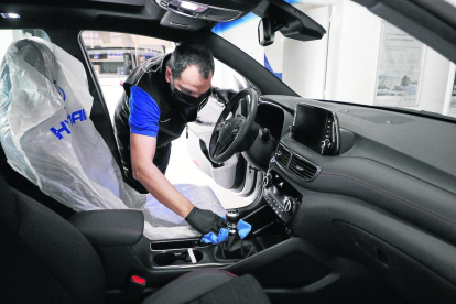 Un trabajador de un taller desinfecta un vehículo, una medida que deben tomar tanto cuando entra como antes de salir del taller. 
