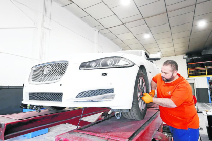 Un treballador d’un taller desinfecta un vehicle, una mesura que han de prendre tant quan entra com abans de sortir del taller.