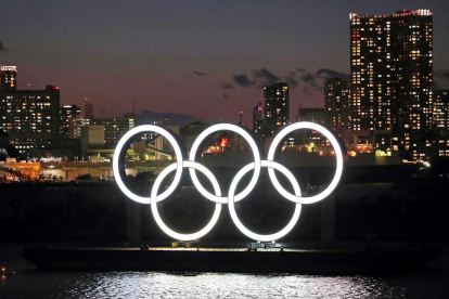 Los aros olímpicos lucen de noche en la bahía de Tokio.