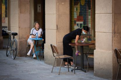 Una cambrera desinfecta les taules i les cadires en un bar de Barcelona.