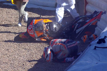 Marc, con el rostro enrojecido, en el box tras la caída. A la derecha, aún en el suelo después de sufrir el aparatoso accidente que dejó prácticamente destrozada la moto.
