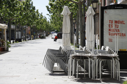 Sillas y mesas de la terraza de un bar apiladas en la Rambla Ferran de Lleida.