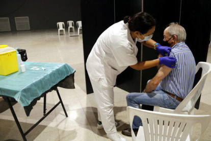 Una enfermera y un hombre a quien le acaban de administrar la vacuna de la gripe en el Espai MerCat de Tàrrega.