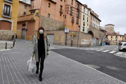 Una dona caminant ahir pel centre de Lleó amb mascareta i una bossa de comprar.