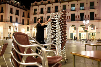Un hostelero recoge la terraza de su establecimiento de Huesca.