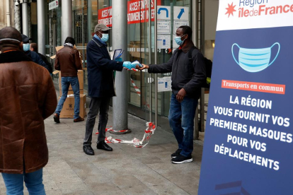 Un voluntari reparteix mascaretes en una estació de París.