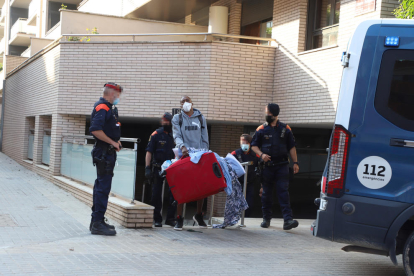 Un dels adults desnonats treu els seus estris al carrer davant la mirada de diversos mossos,
