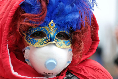 Una persona con la máscara de Carnaval y una mascarilla de papel por el coronavirus.