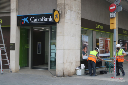Operarios cambiando el logo de Bankia por el de Caixabank.