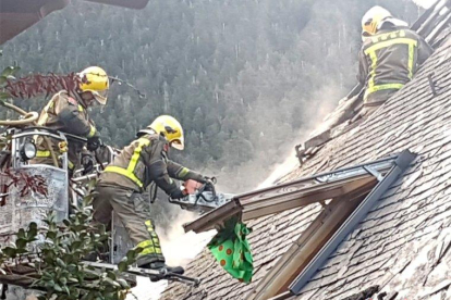 Bomberos sofocando las llamas originadas en una casa adosada. 