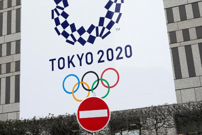 Un senyal de prohibit el pas davant d’un cartell dels Jocs Olímpics.