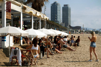 Varias personas disfrutan de un chiringuito este sábado en la playa de la Barceloneta, en Barcelona.