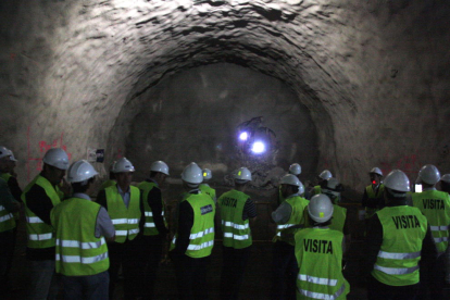 Les autoritats que han assistit a la calada del túnel observen com els operaris fan un forat per unir les dos boques des de l'altre costat.