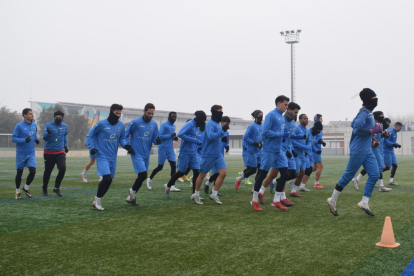 La plantilla del Lleida, durant l’entrenament d’ahir, amb els jugadors protegint-se del fred.