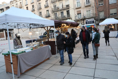 Visitants en una de les parades del mercat, envoltat amb una cinta per controlar l’aforament.