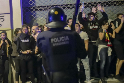 Un mosso davant d’un grup de manifestants, la nit de la vaga del 18-O, a Barcelona.