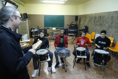 Quatre alumnes seguint les instruccions del professor en una sessió de musicoteràpia.