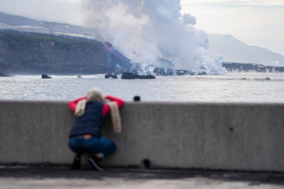 Una persona observa una colada de lava a l’arribar al mar.