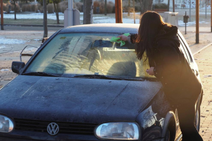Una mujer retira el hielo de su vehículo