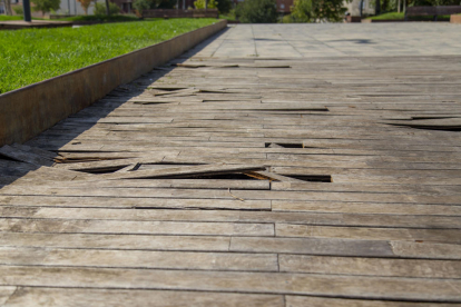 Imagen del pavimento de madera del cubrimiento de las vías, con muchas láminas levantadas.