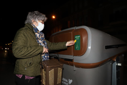 Una veïna de Pardinyes tira l’orgànica en un dels contenidors amb la seua targeta individual.