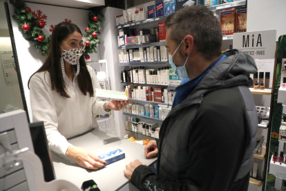 Una empleada de la farmàcia Anadón Solé mostra alguns tests d’antígens a un client, ahir.