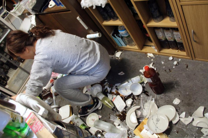 Una mujer inspecciona los desperfectos ocasionados por el terremoto en su local.