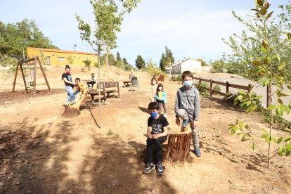 Varios niños de Sucs prueban los nuevos bancos hechos con los tocones de pinos en el parque del Vilot.