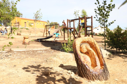 Diversos nens de Sucs proven els nous bancs fets amb les soques de pins al parc del Vilot.