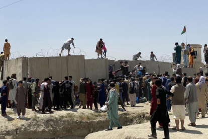 Afganos se agolpan a lo largo del muro del aeropuerto internacional Hamid Karzai antes de saltarlo en un intento de abandonar el país, este lunes en Kabul, después de darse a conocer de que el propio presidente afgano, Ashra Ghani, huyera ayer en secreto.