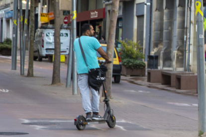 Un conductor de patinet elèctric travessant l’avinguda Catalunya de la capital de l’Urgell.