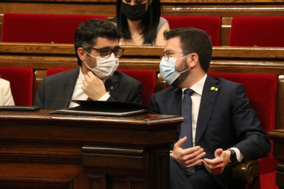 El president del Govern, Pere Aragonès, conversa amb el vicepresident, Jordi Puigneró, durant el ple al Parlament