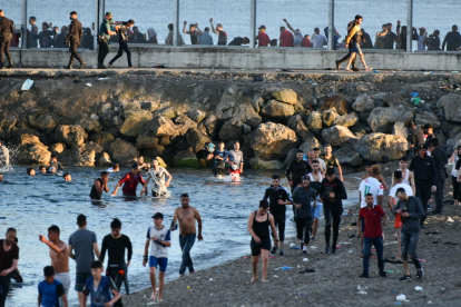 Personas migrantes caminan por la playa del Tarajal, en Ceuta.