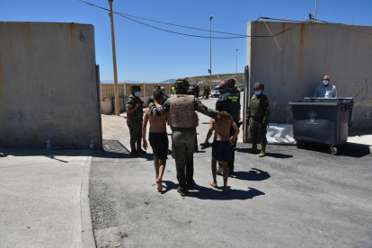Un militar del ejército español y un agente de la Guardia Civil ayudan a dos menores migrantes procedentes de Marruecos a su llegada a Ceuta.
