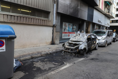 Estado del coche calcinado y de la fachada dañada en la calle Riu Ter. 