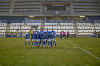 Els onze titulars del Lleida davant del Brea posen abans del partit amb la llotja buida al fons.