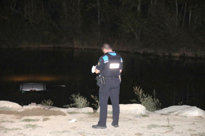 Un urbà ahir a la nit al costat del cotxe, que va quedar submergit al riu a Pardinyes.