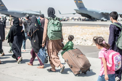 Familias enteras de civiles afganos caminan hacia los aviones que los sacarán del país.