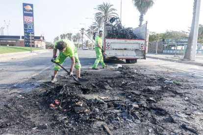 Operarios de la limpiezan retiran restos calcinados durante el último macrobotellón en Barcelona.