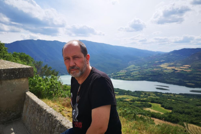 El artista de Tremp Àlvar Calvet en Llimiana, con el pantano de Cellers al fondo. A la derecha, las monedas que ofrecerá a los visitantes.