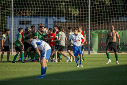 Adrià Fernández, sin camiseta, celebra con sus compañeros del Ascó el ascenso mientras en primer plano dos jugadores del Mollerussa muestran su abatimiento.
