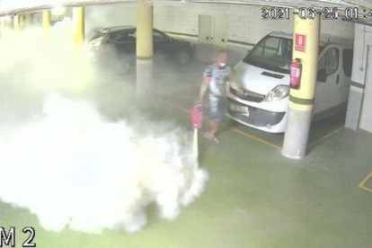 Imatge de la càmera de seguretat d'un dels aparcaments comunitaris on es pot veure el detingut buidant un extintor.