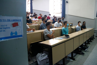 Estudiantes universitarios con mascarilla dentro de un aula.