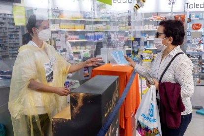 Una mujer adquiere un paquete de mascarillas en una farmacia.