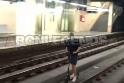 Graven un noi anant en patinet elèctric per les vies del tren a Barcelona