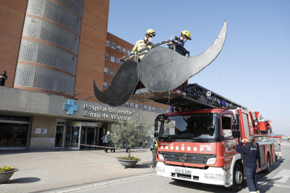 Los Bomberos del parque de Lleida colocando ayer el bigote gigante con un camión-escalera. 