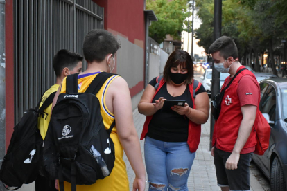Dos voluntaris de Creu Roja parlant amb dos joves a Lleida.