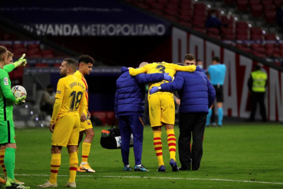 Gerard Piqué es retira del terreny de joc del Wanda ajudat per membres del seu equip.
