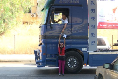 Una niña vende agua a un camionero, en Beirut.